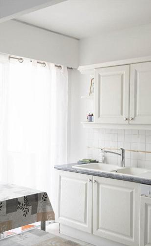 une cuisine blanche avec un évier et une fenêtre dans l'établissement Appartement 2 pièces Cavalaire sur Mer 60m2, à Cavalaire-sur-Mer