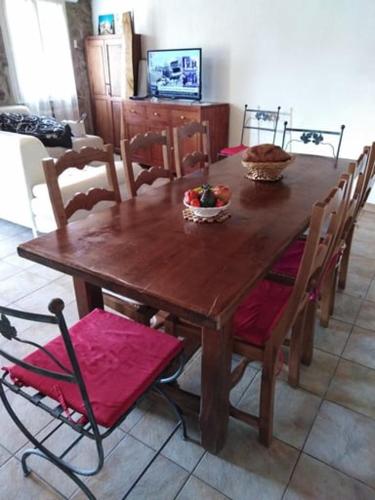 une table de salle à manger en bois avec des chaises et une table et une télévision dans l'établissement LES SOURCES du CHASSEZAC, à Saint-Chaptes