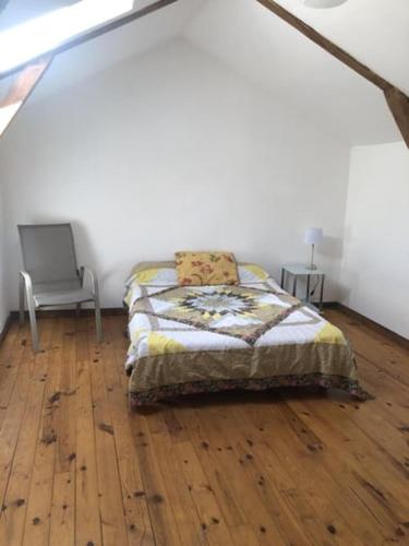 - une chambre avec un lit et une chaise sur du parquet dans l'établissement LES SOURCES du CHASSEZAC, à Saint-Chaptes