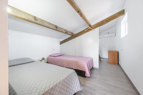 two beds in a room with white walls and wooden floors at Casa da raposeira in Louredo
