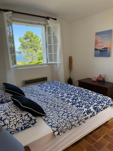 - une chambre avec un lit bleu et blanc et une fenêtre dans l'établissement Le Fagneton - Seaview Villa Cote d'Azur, à Roquebrune-sur Argens
