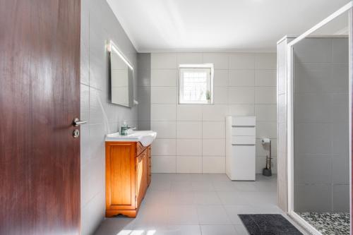 a white bathroom with a sink and a mirror at Casa da raposeira in Louredo