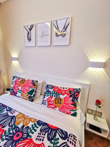 a bedroom with a bed with colorful pillows and pictures on the wall at LuxuryStay by Al Amir in Martil