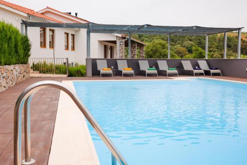 a swimming pool with chairs and a house at Estrela de Montesinho in Bragança