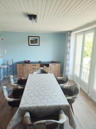 a dining room with a table and chairs and windows at Gite du Goulet in Montusclat