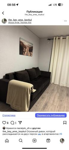 a living room with a black couch in a room at Квартиры под соснами in Cholpon-Ata