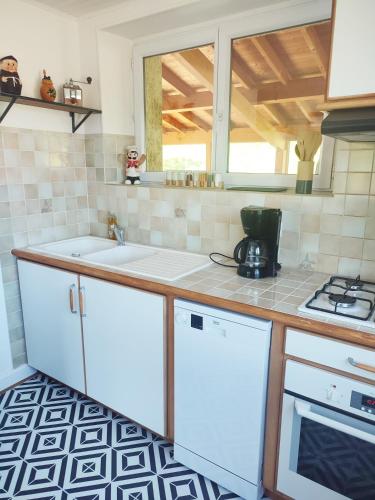 a kitchen with white cabinets and a sink and a window at Gite du Goulet in Montusclat