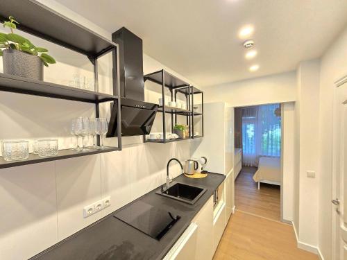 eine Küche mit schwarz-weißen Schränken und einer Spüle in der Unterkunft Haustory Palanga Apartment in Palanga