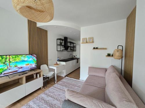 ein Wohnzimmer mit Couch und Flachbildfernseher in der Unterkunft Haustory Palanga Apartment in Palanga