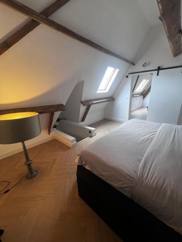 a bedroom with a bed and a lamp in a attic at The Cotton Suites B&B in Deerlijk