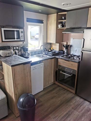 Il comprend une cuisine équipée d'un réfrigérateur et d'une cuisinière. four supérieur dans l'établissement Mobil-home 8 places camping 4, à Pont-Aven