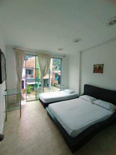 a bedroom with two beds and a large window at Hotel Cascada Cristalina in Melgar