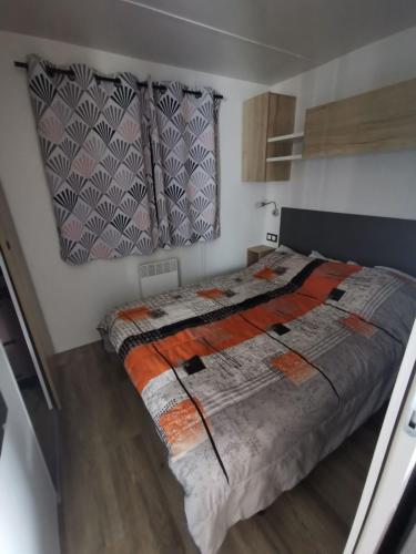 une chambre avec un lit avec une couette orange et grise dans l'établissement Mobil-home 8 places camping 4, à Pont-Aven
