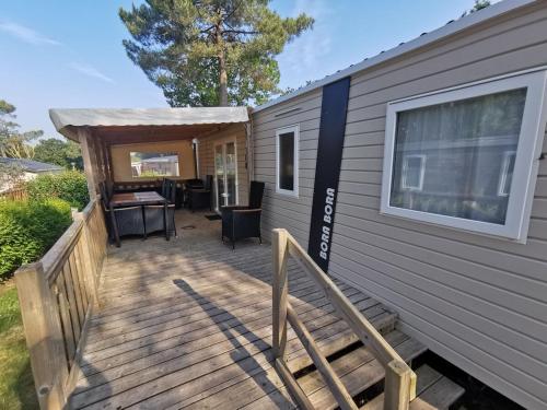 a deck with a table and a house at Mobil-home 8 places camping 4 in Pont-Aven
