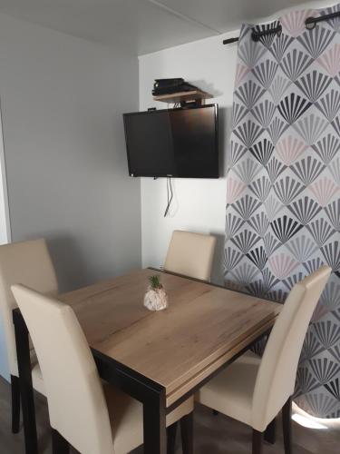 a wooden table with white chairs and a tv on a wall at Mobil-home 8 places camping 4 in Pont-Aven