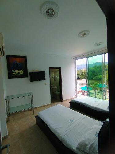a bedroom with two beds and a view of a pool at Hotel Cascada Cristalina in Melgar