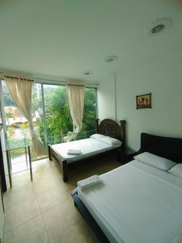 a bedroom with two beds and a large window at Hotel Cascada Cristalina in Melgar