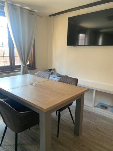 a dining room table with chairs and a television at St Faith's Chambers in Maidstone