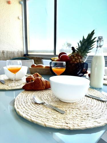 une table avec une assiette de nourriture et des verres de jus d'orange dans l'établissement L'Escapade Valrassienne - 5 minutes de la plage, à Valras-Plage