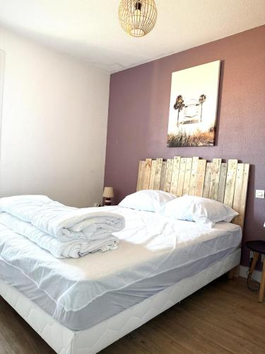 une chambre avec un lit blanc avec une tête de lit en bois dans l'établissement L'Escapade Valrassienne - 5 minutes de la plage, à Valras-Plage