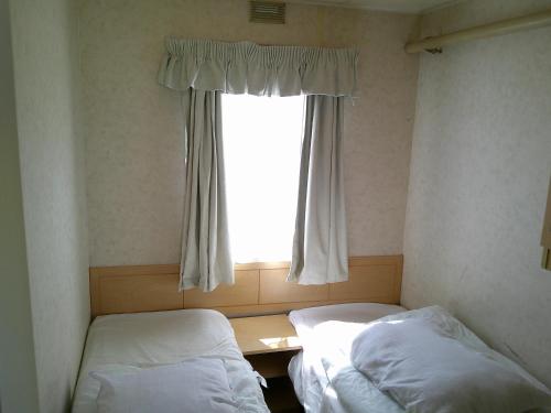 une petite chambre avec deux lits et une fenêtre dans l'établissement Golden Palm Mirage GP 6 Berth enclosed veranda, à Chapel St. Leonards