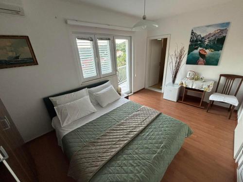 a bedroom with a bed and a table with a chair at Bjelopera Rooms in Zaton