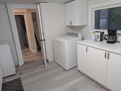 a kitchen with white cabinets and a washer and dryer at Cozy Bachelor Unit in Guelph