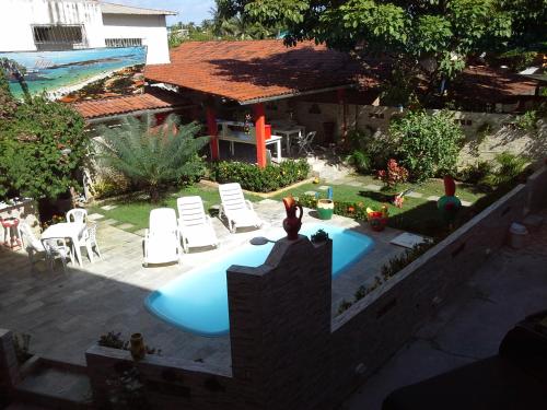 a backyard with a swimming pool and chairs and a house at Swiss Flats in Porto De Galinhas