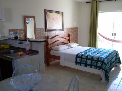 a bedroom with a bed and a table and a sink at Swiss Flats in Porto De Galinhas