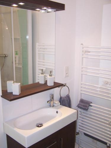 une salle de bain blanche avec un lavabo et un miroir dans l'établissement Gîte Mosaïque, à Arras