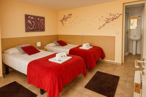 a hotel room with two beds with red sheets at Pensión O Muiño in O Pedrouzo