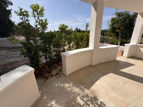 a patio with a white wall and trees at Casa Daniel in Selva di Fasano