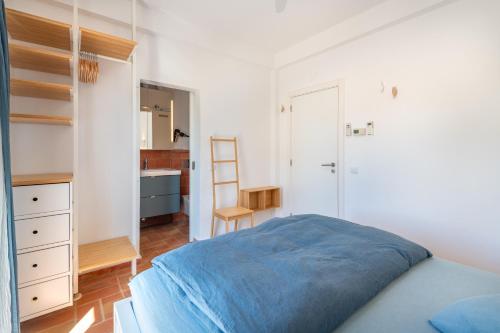 a bedroom with a blue bed and a bathroom at Terracotta Room in Moncarapacho