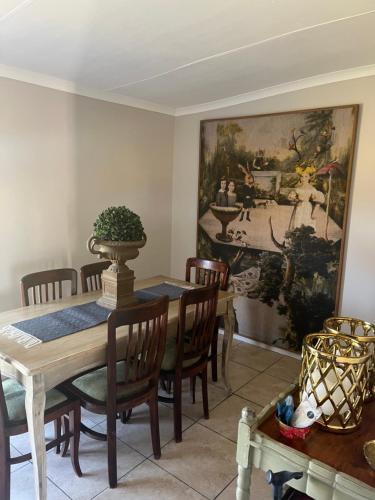 Un comedor con una mesa y sillas y un cuadro. en Die Wit Haas, en Nieuwoudtville