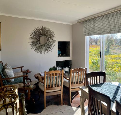 Una sala de estar con una mesa y sillas y un espejo. en Die Wit Haas, en Nieuwoudtville