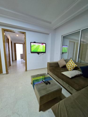 a living room with a couch and a tv on a wall at luxury Appartment in Carthage