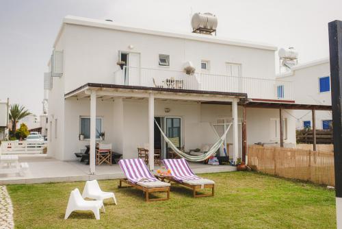 a house with two chairs and a hammock in the yard at Ammos Beachfront Villa Paradise in Larnaka