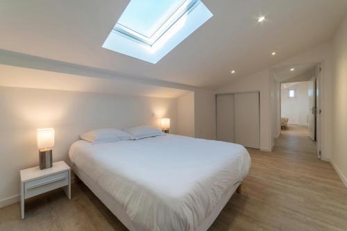 - une chambre avec un grand lit blanc et une lucarne dans l'établissement Le Sweet Duplex, à Mulhouse