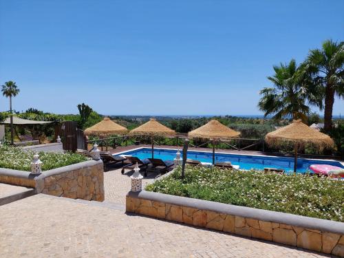 a resort with a swimming pool and straw umbrellas at Retiro da Janela in Boliqueime