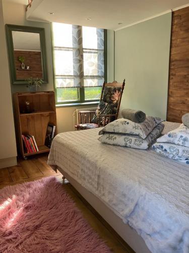 a bedroom with a bed with a mirror and a pink rug at Stationshus apartment in Hallstahammar