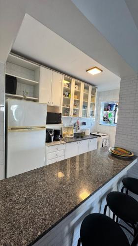 a kitchen with white cabinets and a white refrigerator at Apê dos Meninos no Forte in Praia Grande