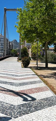 a sidewalk with a tree and a bridge at El apartamento Cristina in Gandía
