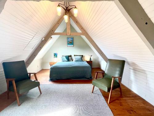 - une chambre mansardée avec un lit et deux chaises dans l'établissement Chez Nosch, à Plouégat-Guérand