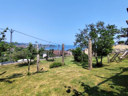 a field with trees and the ocean in the background at A Barraca. Casa con jardín y vistas a la ría in Bueu