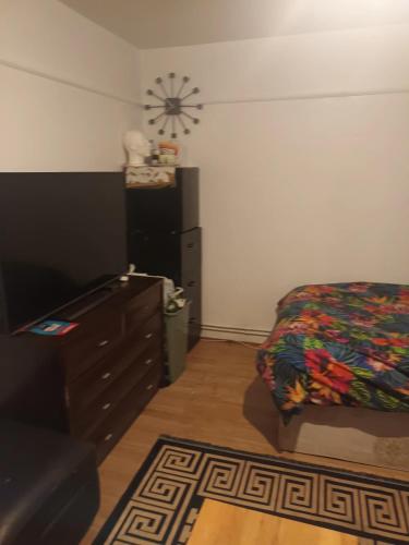 a bedroom with a bed and a dresser and a clock on the wall at Super Large Double Room in Abbey Wood