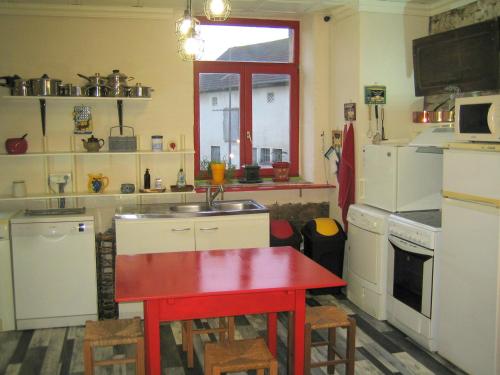 - une cuisine avec une table rouge et un évier dans l'établissement Gîte et Grange à Jeux du Bonhomme Bouton, à Guinzeling