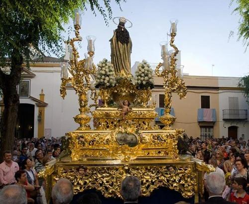 a crowd of people standing around a large gold float at Apartamento_Santa Isabel in Utrera