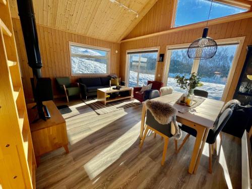 a living room with a table and chairs and windows at Hytte sentralt i Myrkdalen in Vossevangen