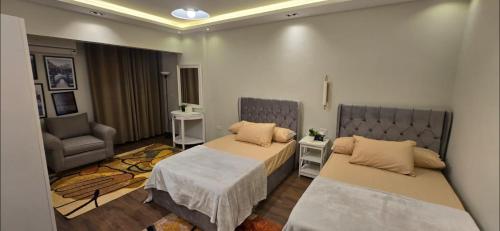 a bedroom with two beds and a chair at The Zamalek Residence in Banī Ghālib