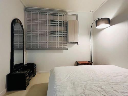a bedroom with a bed and a lamp and a window at Re STAY in Daegu